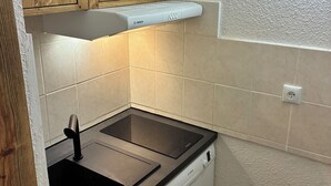 Eine kompakte Küche mit Holzschränken, einem Geschirrspüler von Bosch und einer schwarzen Arbeitsplatte.