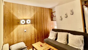 Ein gemütliches Wohnzimmer mit einer Holzvertäfelung, einem dunkelgrauen Sofa und einem kleinen Holztisch.