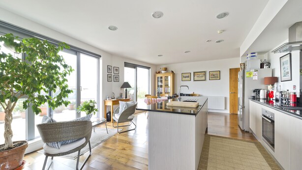 A modern kitchen with a central island, wooden flooring, and a large window providing natural light. - Putney Rooftops - Two Bedroom Apartment, Sleeps 4 (London)