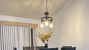 Un comedor con una mesa de madera, sillas oscuras y una lámpara colgante.