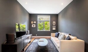 Relax in this stylish living room with a large window, flat-screen TV, and comfortable sofa.