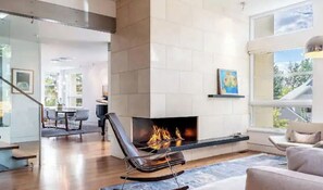 Cozy living space with a fireplace, dining area, and staircase leading to an upper level.