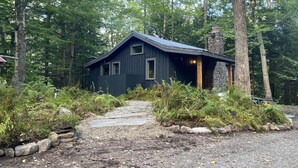 Une cabane dotée d’un toit en pente, entourée d’une forêt dense.