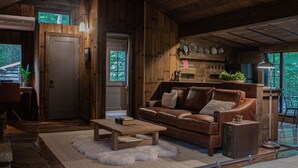 L’intérieur d’un chalet rustique est agrémenté d’un canapé en cuir, d’une table basse en bois et d’un coin repas.