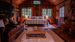 Une chambre confortable dans un chalet en rondins, avec un grand lit, un canapé en cuir et une cheminée en pierre rustique.