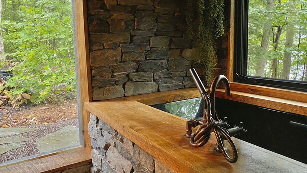 L’intérieur d’un chalet rustique, avec un mur en pierre, un banc en bois et un vélo.