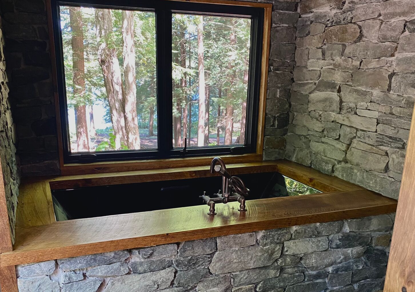 A stone wall with a wooden window frame and a built-in sink.