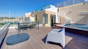En solbeskinnet terrasse med pool, udendørs møbler og trapper op til en øvre etage.