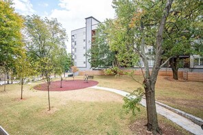 A courtyard with trees, a red circular area, and a modern building with balconies.
