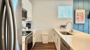 A modern kitchen with white cabinets, stainless steel appliances, and a window with blinds. - Stylish 2B2B Apartment in Atlanta's Old Fourth Ward (Atlanta)
