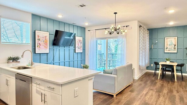 A modern kitchen with a central island, a dining area with a table and chairs, and a living space with a sofa. - Stylish 2B2B Apartment in Atlanta's Old Fourth Ward (Atlanta)