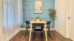 A dining area with a wooden table and black chairs, a blue paneled wall, and a framed artwork above the table. - Stylish 2B2B Apartment in Atlanta's Old Fourth Ward (Atlanta)