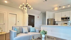 A modern living room with a grey sofa, a glass coffee table, and a unique chandelier. - Stylish 2B2B Apartment in Atlanta's Old Fourth Ward (Atlanta)