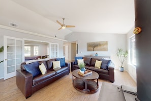 A spacious living room with two brown leather sofas, a wooden coffee table, and a ceiling fan. - Mountain-view home with a game room, washer/dryer, firepit, AC & basketball (Oakhurst)