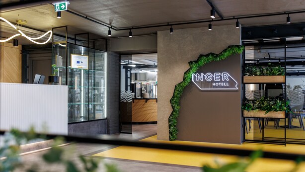 A modern hotel lobby with a reception desk, glass partitions, and a sign reading "INGER HOTEL".