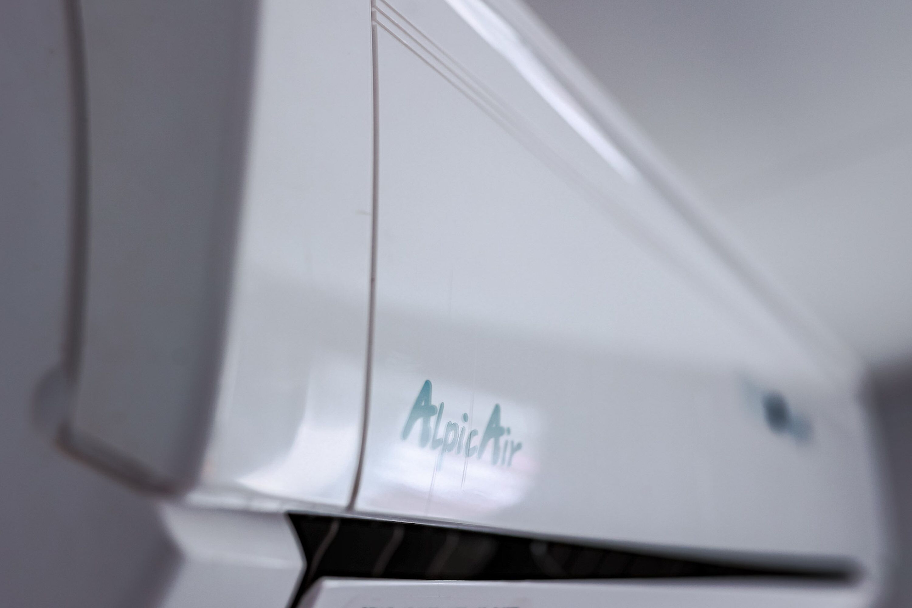 Un appareil de climatisation blanc, sur lequel on peut voir le nom de la marque « AlpicAir ».