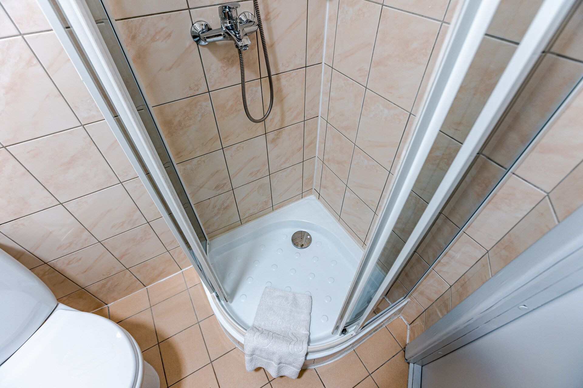 Una esquina de un baño con ducha, inodoro y paredes de azulejos.