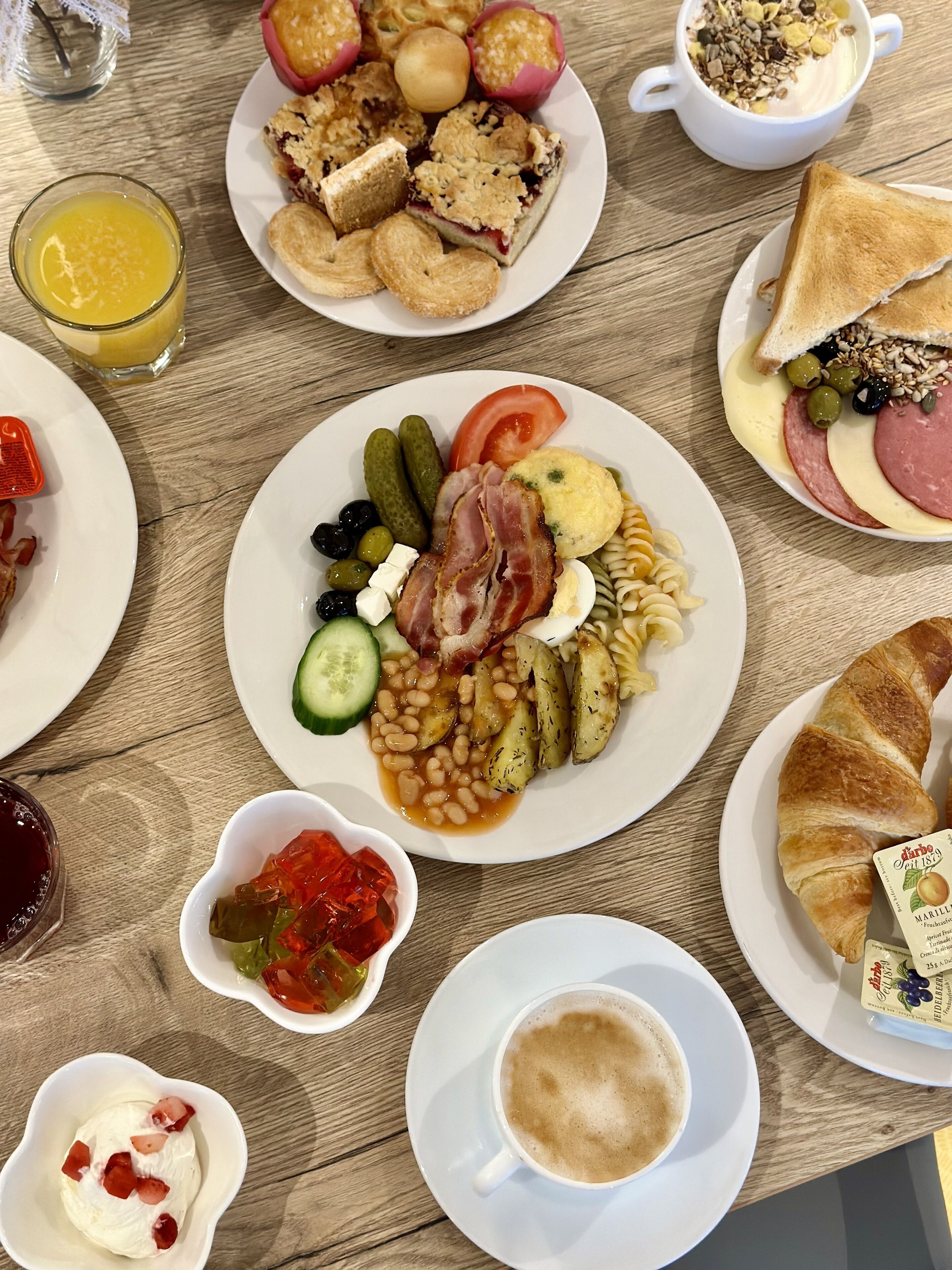 Una mesa de desayuno con diversos platos, incluyendo huevos, tocino, tomates y pan.