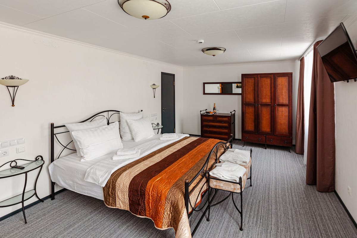 A neatly arranged bedroom with a bed, bedside table, and a wooden wardrobe.