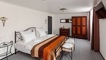 A neatly arranged bedroom with a bed, bedside table, and a wooden wardrobe.