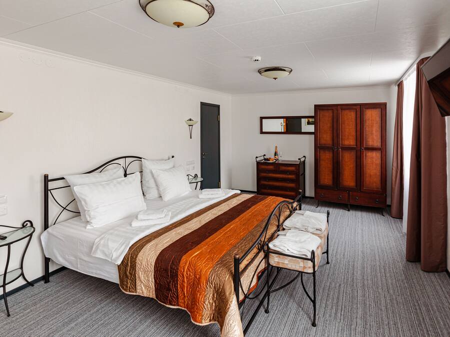 A neatly arranged bedroom with a bed, bedside table, and a wooden wardrobe.