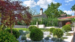A garden with a stone building, surrounded by various shrubs and trees. - Luxuriously decorated villa with designer interior, pool, sauna and wellness (Pićan)