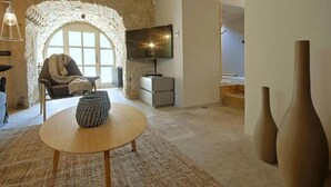 A cozy living room with a stone archway, a comfortable chair, a television, and a round wooden table. - Luxuriously decorated villa with designer interior, pool, sauna and wellness (Pićan)