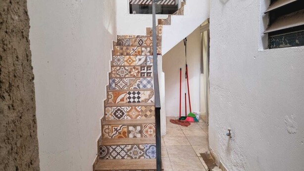 A narrow staircase with a variety of patterned tiles leading to a landing. - Apartamento completo (Guaratingueta)