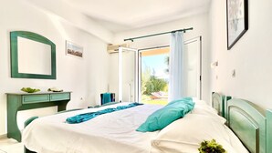 A bedroom with a bed, a dresser, a mirror, and a window with curtains.