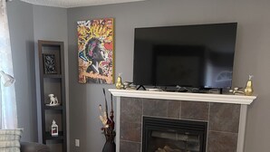 Ein Wohnzimmer mit Kamin, Flachbildfernseher, Sofa und Couchtisch.