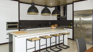 A modern kitchen with a central island, bar stools, stainless steel appliances, and pendant lighting. - Perfectly located in Playa Guiones. Walk to the beach, shops, restaurants & yoga (Nosara)