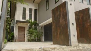 A modern two-story house with a garage, large windows, and a covered driveway. - Perfectly located in Playa Guiones. Walk to the beach, shops, restaurants & yoga (Nosara)