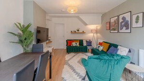 A modern living room with a TV, sofa, and a dining area. - Central 3 Bedroom House With Garden (London)