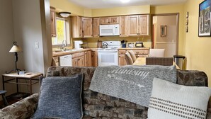 Un salón acogedor con un sofá, una mesa y una cocina al fondo.