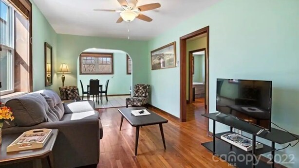 A living room with a sofa, coffee table, TV, and a ceiling fan.
