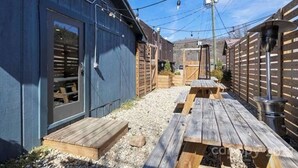 A backyard with wooden picnic tables and a blue building.