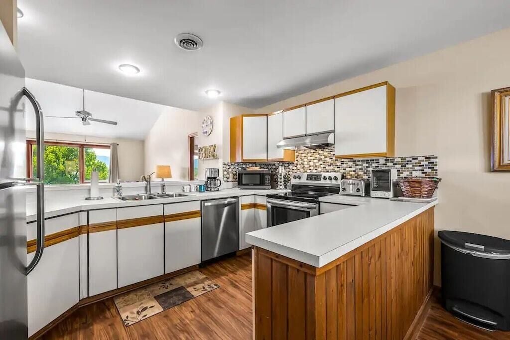 A modern kitchen with white cabinets, a wooden island, stainless steel appliances, and a tiled backsplash.