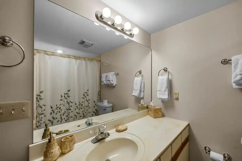 Un baño con un espejo grande, un lavabo y una cortina de ducha.