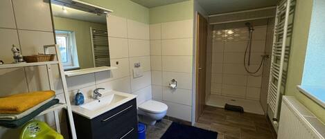 Un baño pequeño con un lavamanos blanco, un inodoro y una zona de ducha.