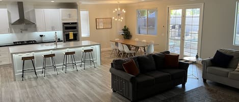 Una cocina moderna con una isla central, taburetes de bar y un comedor con mesa y sillas.