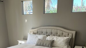 A bedroom with a tufted headboard, white bedding, and two bedside tables.