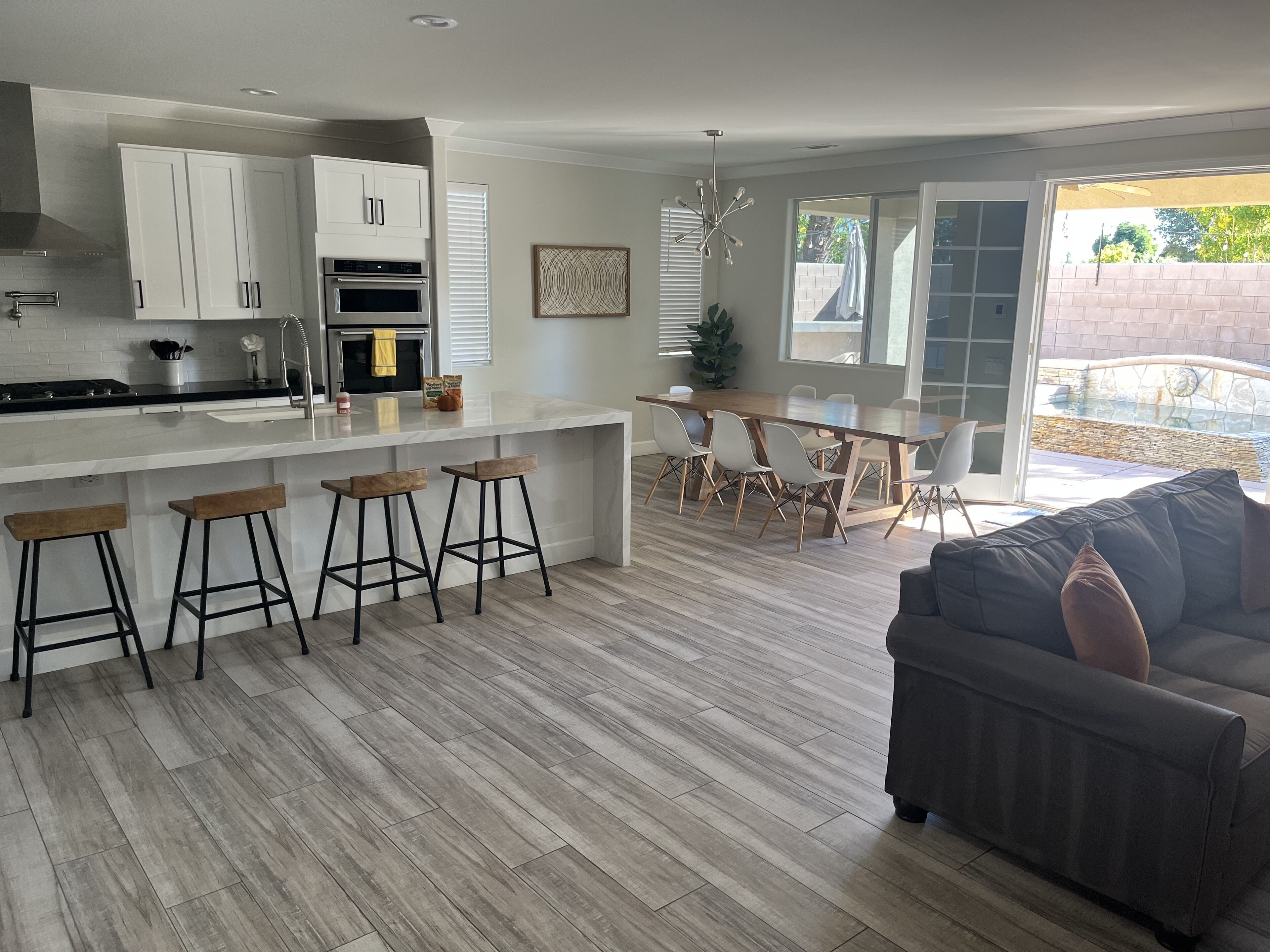 Une cuisine moderne avec des meubles blancs, un îlot central doté de tabourets et un coin repas avec une table et des chaises.