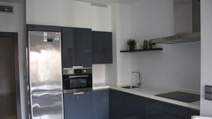A modern kitchen with a stainless steel refrigerator, built-in oven, and a sleek countertop.