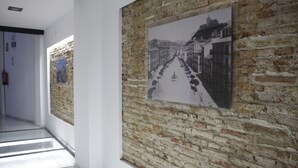A corridor with a brick wall and a framed black and white photograph.