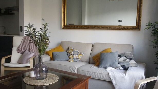 A living room with a sofa, armchairs, a coffee table, and a mirror on the wall.