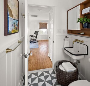 A bathroom with a white sink, a wooden chair, and a wicker basket. - #15 Dog-Friendly 2BR Ocean-Block Cottage with Private Drive in Rehoboth Beach (Rehoboth Beach)