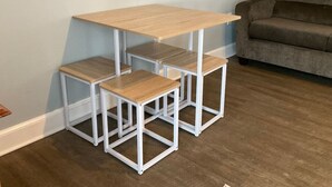 A corner table with a wooden top and white metal frame, accompanied by two matching stools. - * *Oceanfront | Hampton Beach | Pet Friendly* * (Hampton)