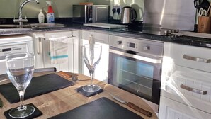 A modern kitchen with white cabinets, a stainless steel range, a microwave, and an oven. - Bowness Hideaway (Windermere)