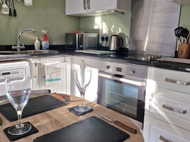 Uma cozinha moderna com armários brancos, fogão de aço inoxidável, micro-ondas e forno.