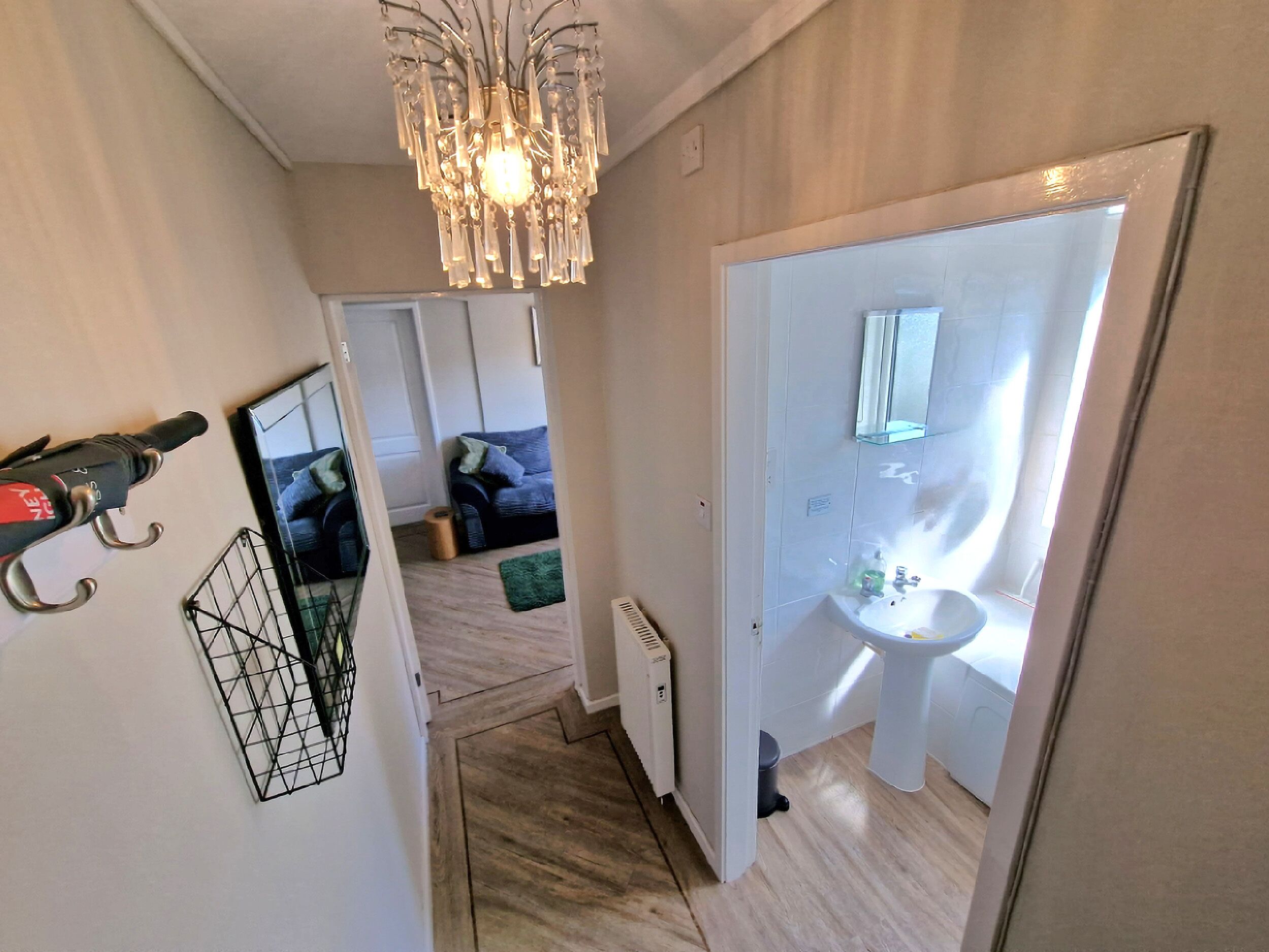 Un couloir avec un radiateur, un miroir et un lavabo dans une salle de bain.